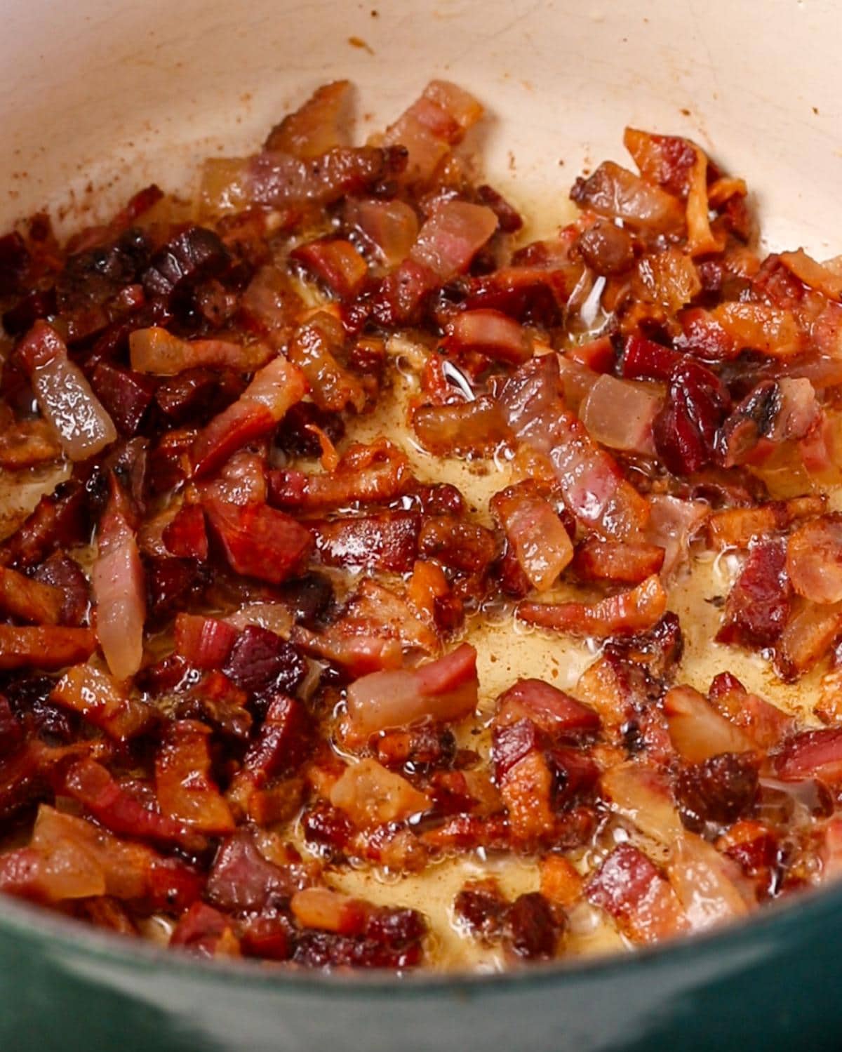 Pancetta cooking in a pan until golden and the fat has rendered.