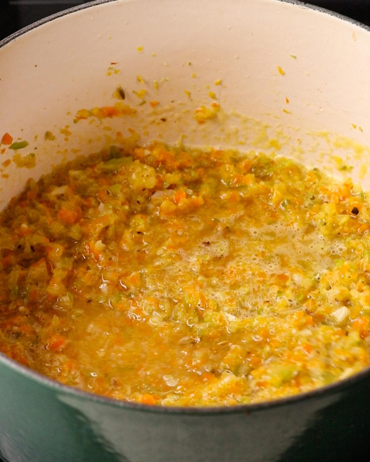 White wine being poured into the soffritto for chicken ragu.