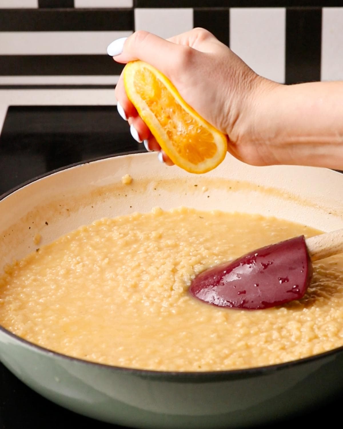 Fresh lemon juice being squeezed over finished parmesan pastina.